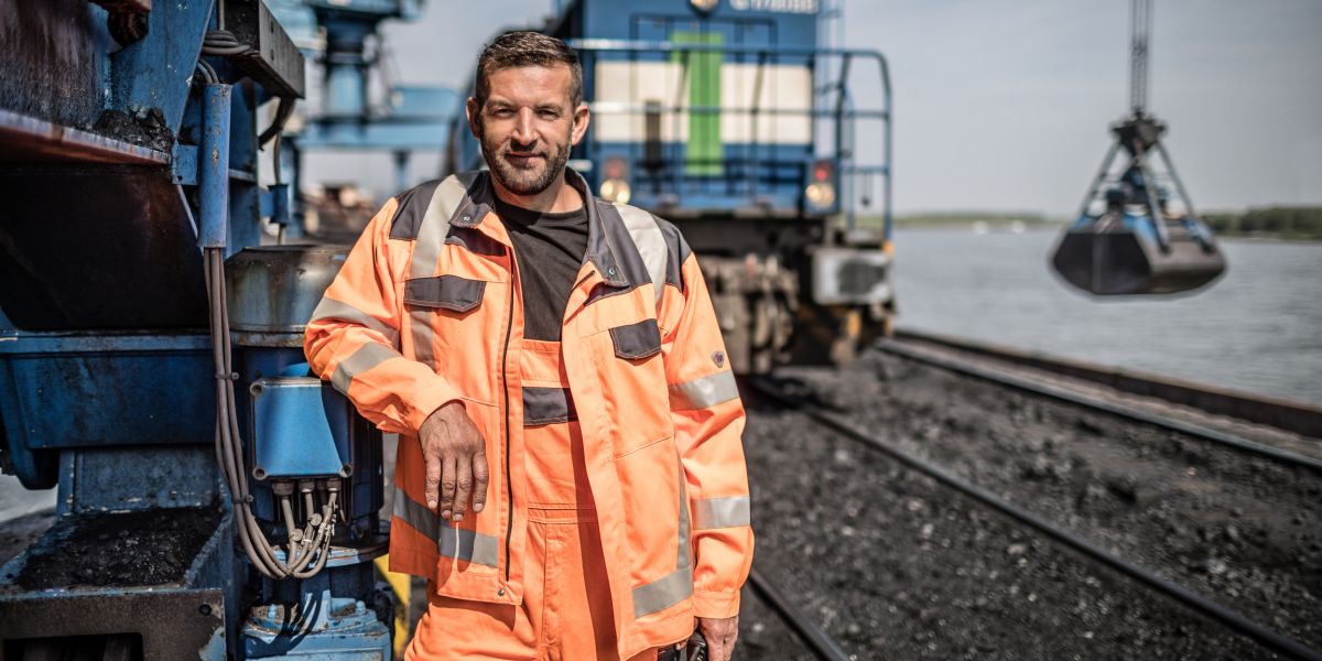Ein Mitarbeiter im Rheinhafen Orsoy vor einem Güterzug und dem Hafenkran.